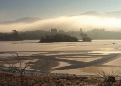 Misty landscape with a castle on an island in a lake.