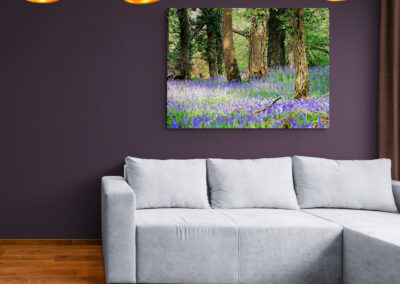 Modern living room with gray sofa, bluebell forest wall art, and pendant lights. Interior design.