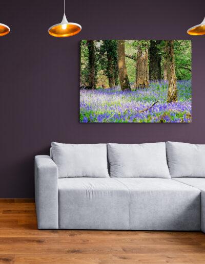 Modern living room with gray sofa, bluebell forest wall art, and pendant lights. Interior design.