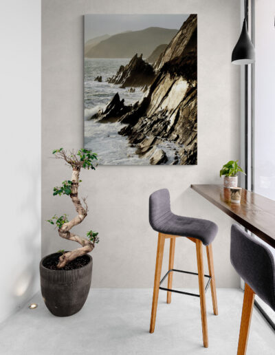 Modern interior with coastal decor: art print of rocky coastline, bonsai tree, and bar seating.