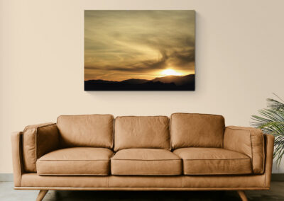 Sunset landscape art over a brown leather sofa, enhancing home decor.