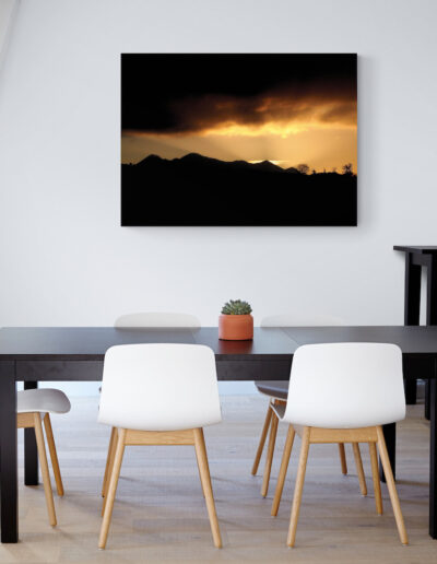 Modern dining room with black table and white chairs, featuring landscape art.