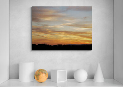 Sunset landscape photograph with orange and blue sky over silhouetted trees