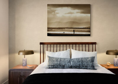 Cozy bedroom with wooden headboard, marble lamps, and beach scene artwork, perfect for bedroom decor.