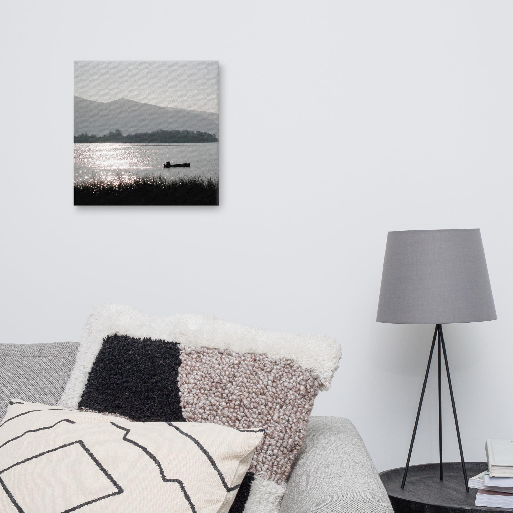 Silhouette of a fisherman in a boat on Lough Leane with mountains in the background.