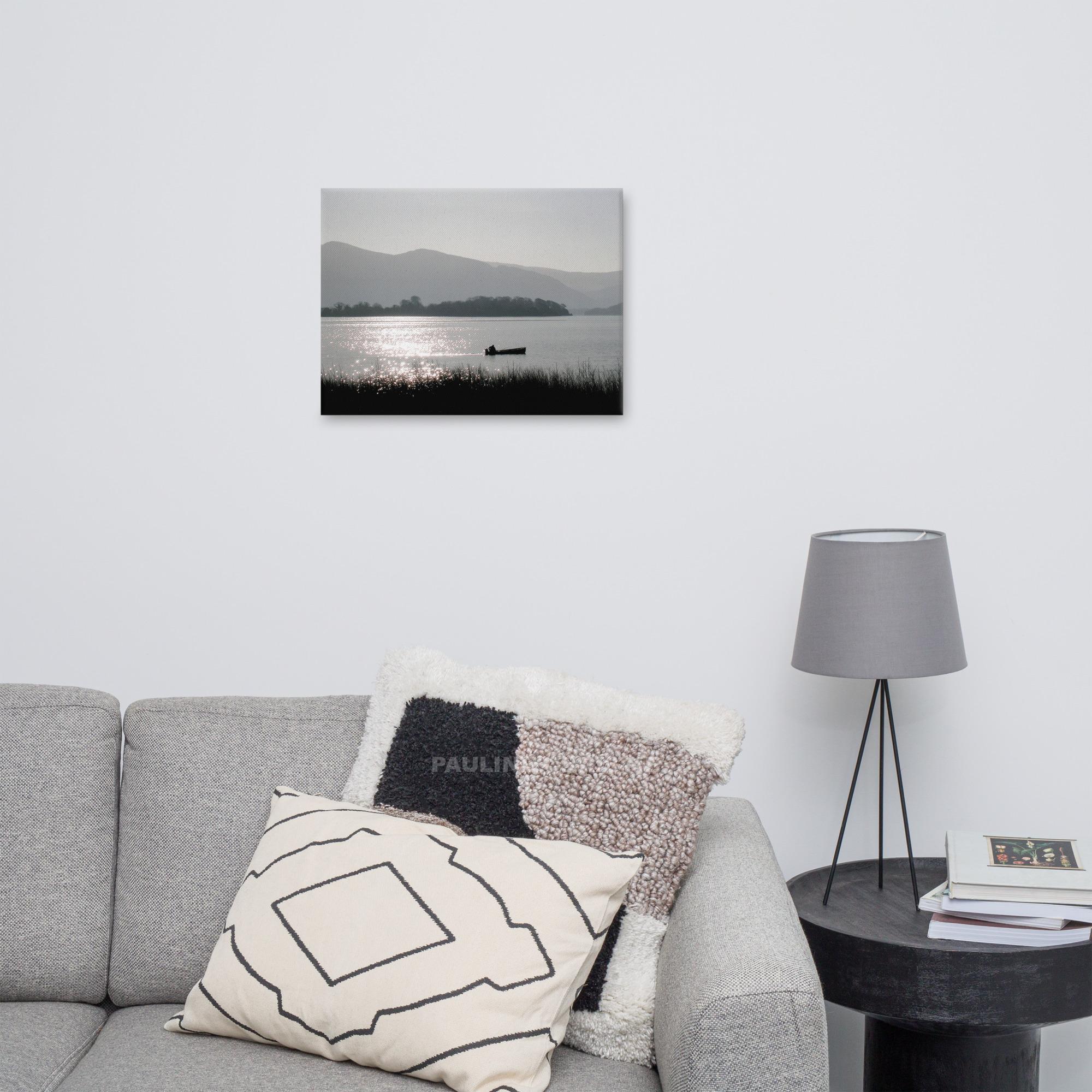 Silhouette of a fisherman in a boat on Lough Leane with mountains in the background.