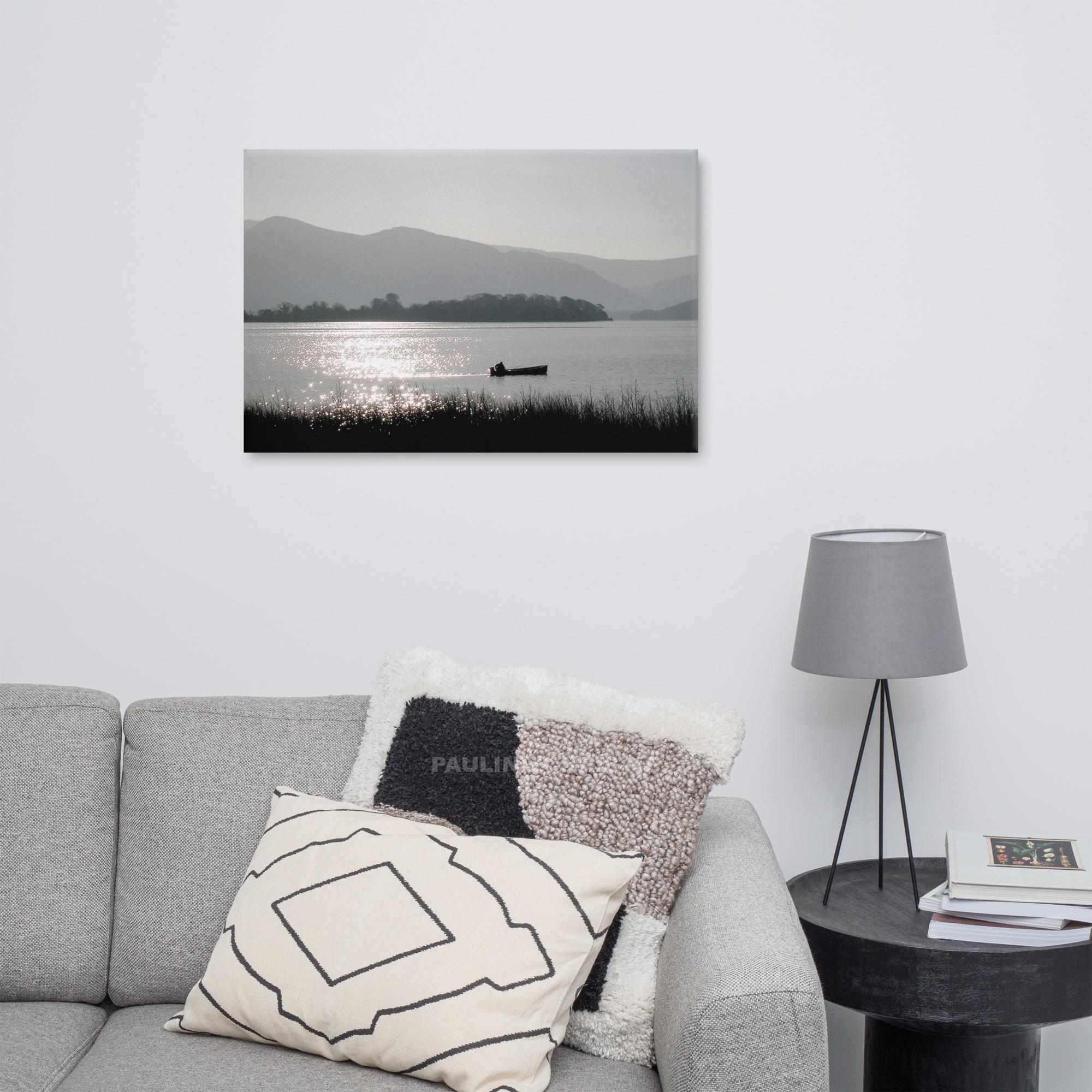 Silhouette of a fisherman in a boat on Lough Leane with mountains in the background.